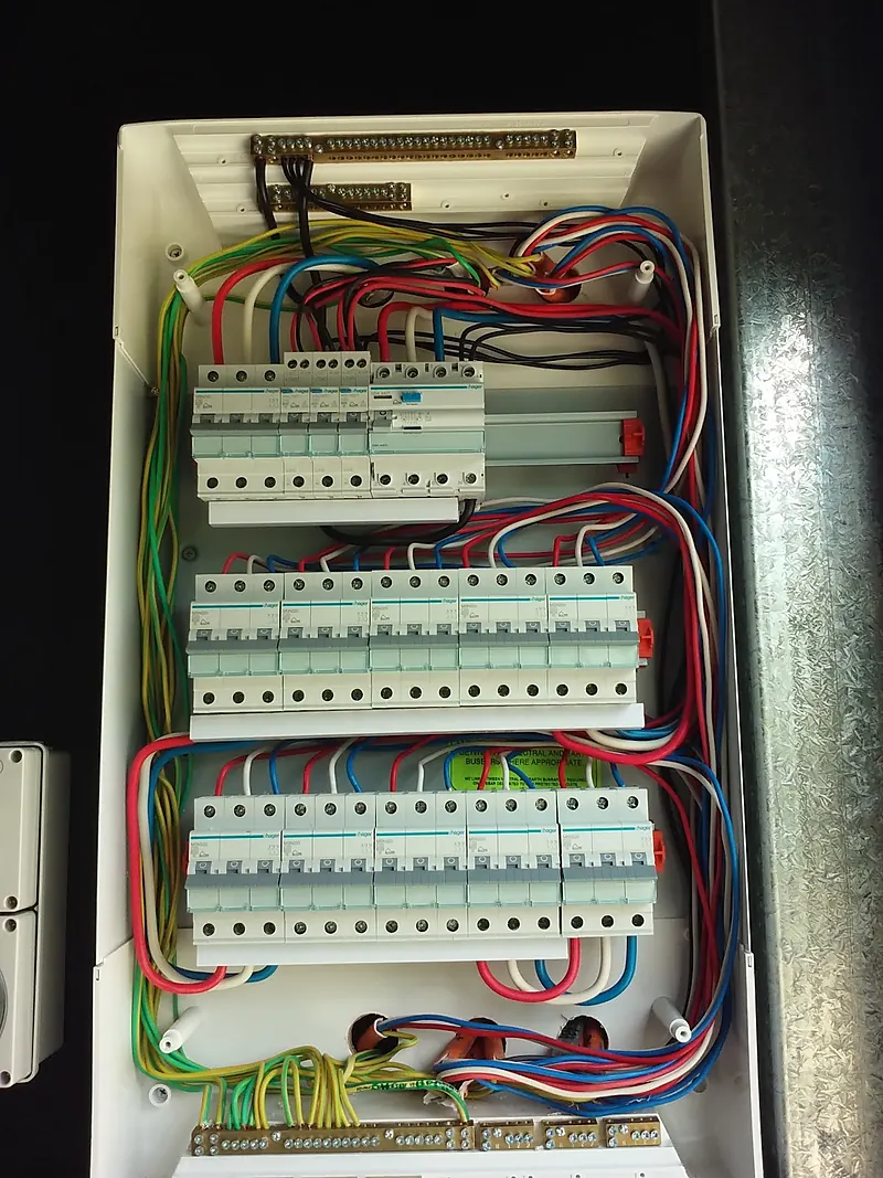 Switchboard with three rows of breakers and safety switches, wiring neatly loomed